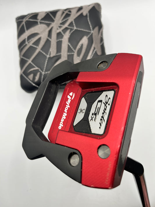 Red TaylorMade golf putter with black accents on a white background