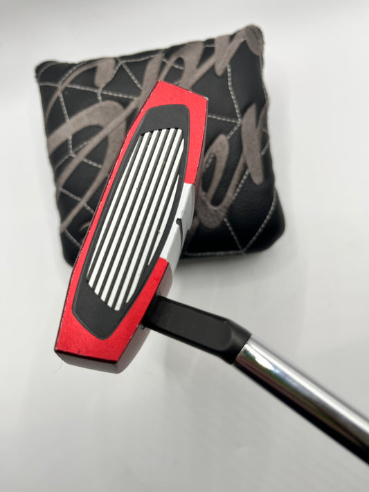 Golf putter with red and black design on a white background