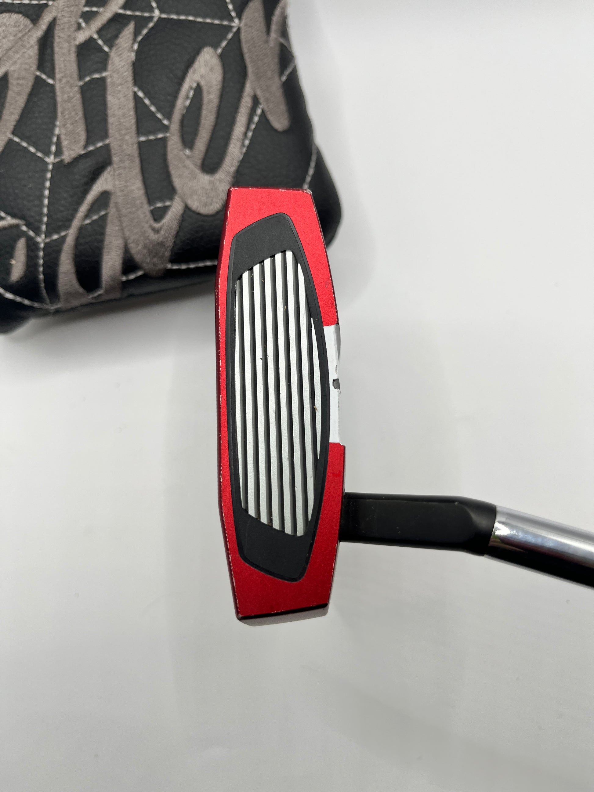 Close-up of a golf putter with a red and black head on a white background