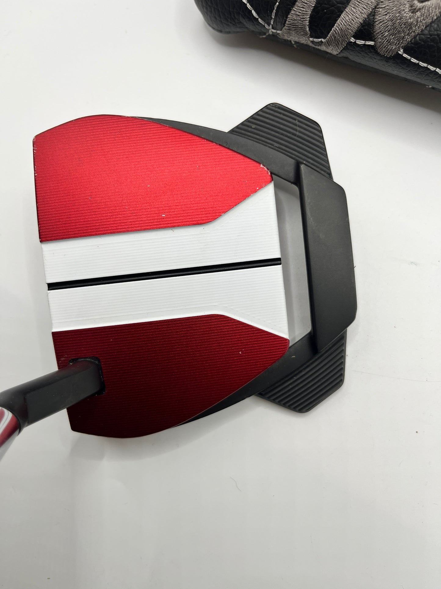 Close-up of a golf putter with red and black design on a white background