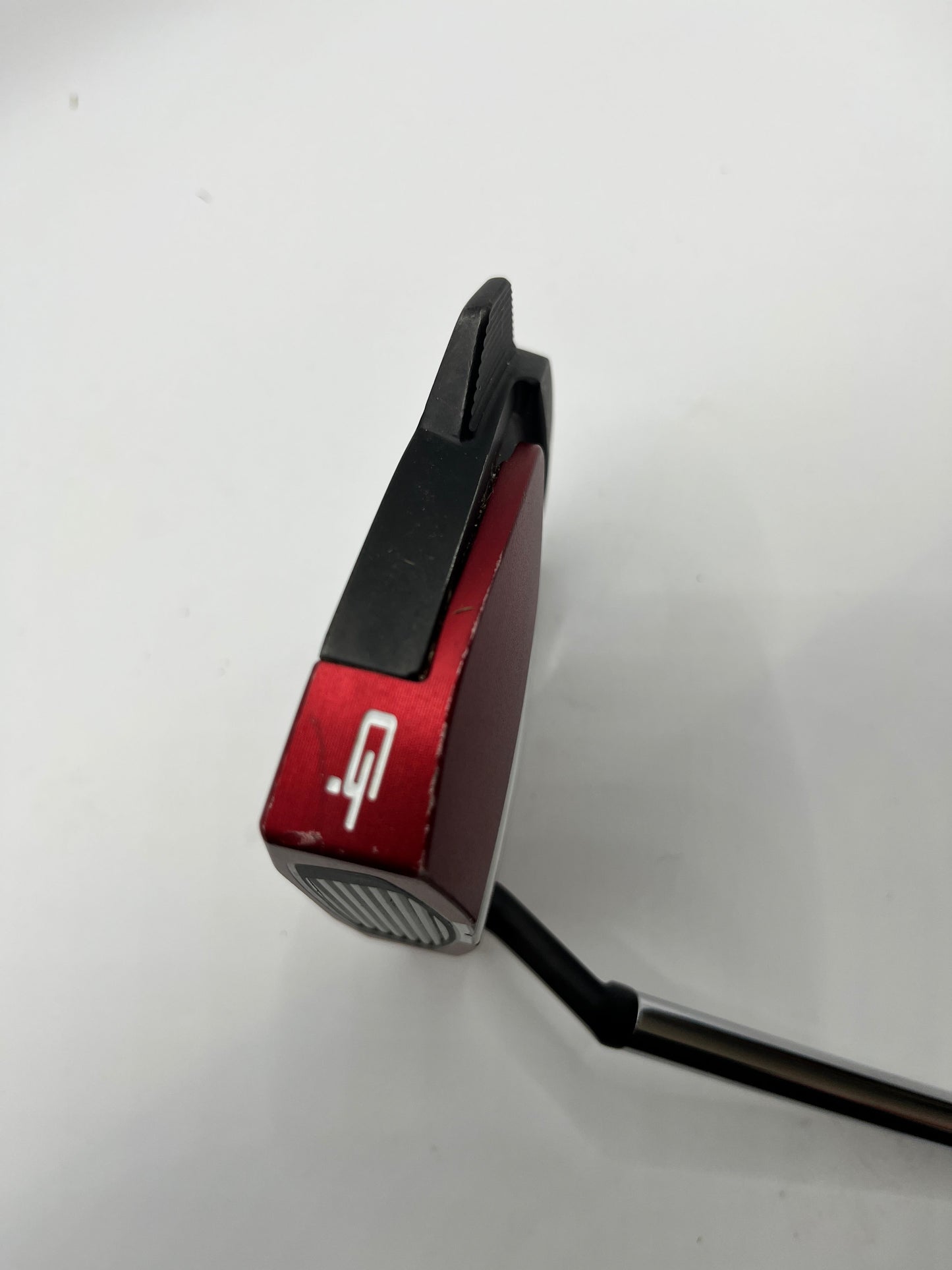 Red and black golf putter on a white background
