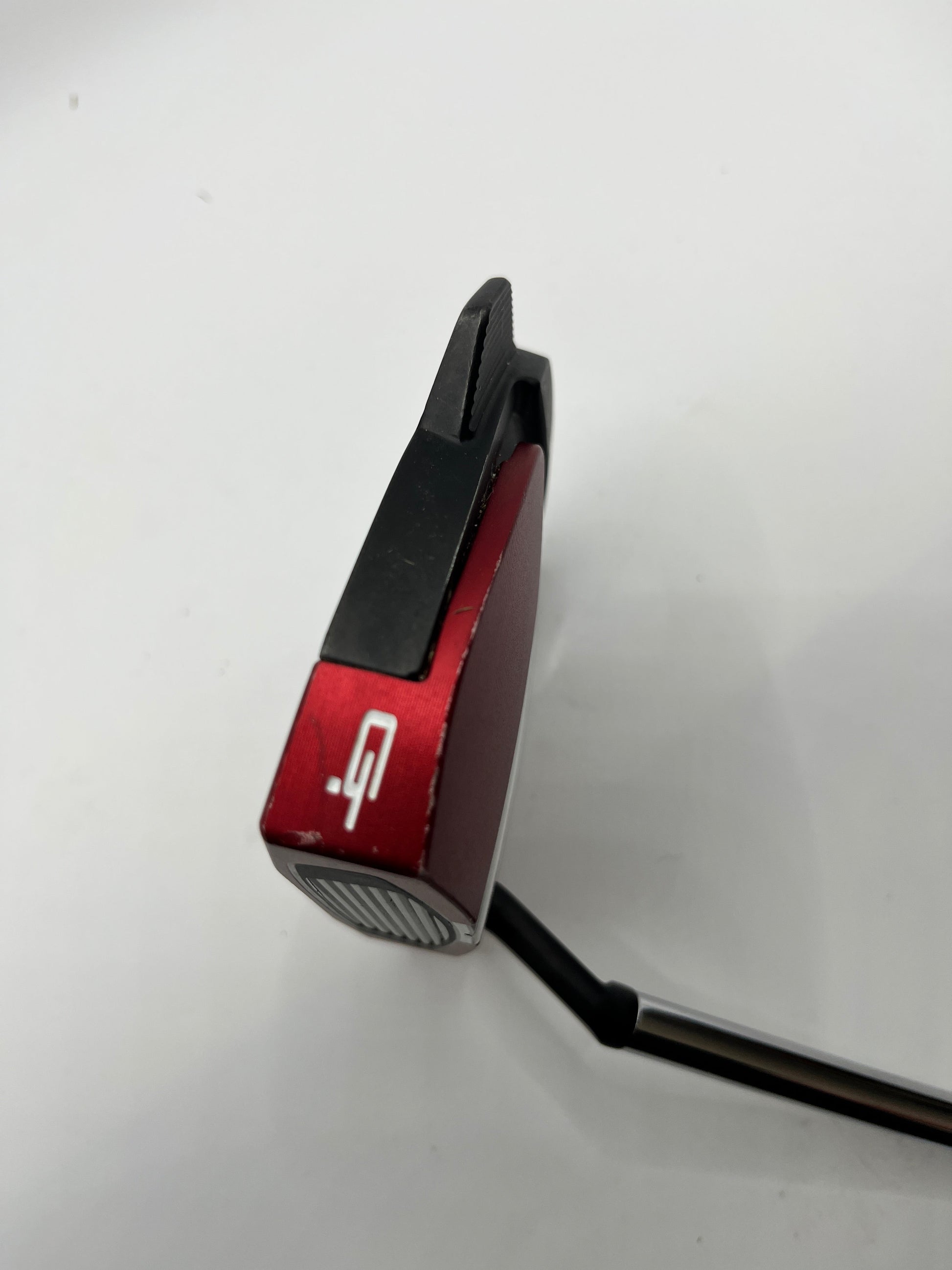 Red and black golf putter on a white background