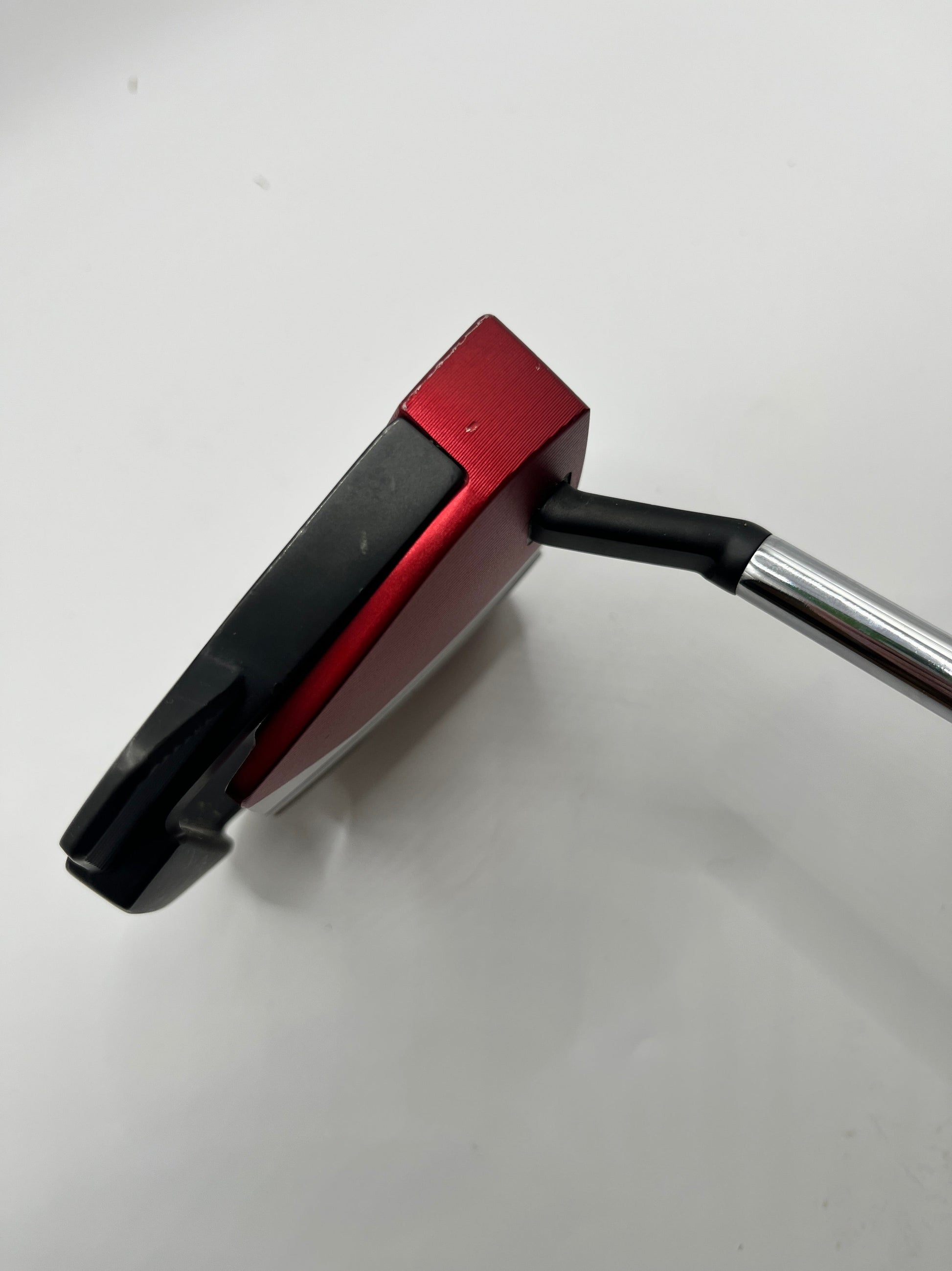 Golf putter with red and black head on a white background
